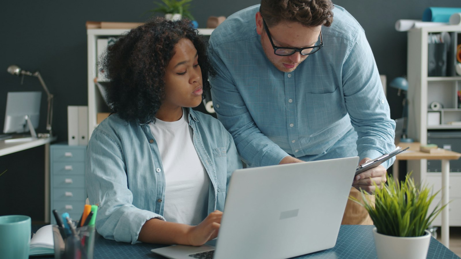 A manager coaching a colleague at a laptop